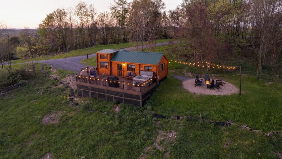Cabin with string lights and a fire pit seating area, nestled near trees