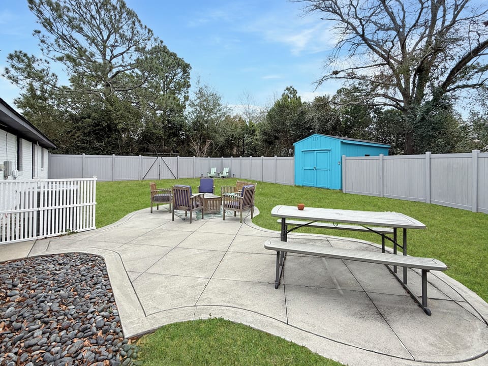 Spacious fenced yard with patio seating and picnic table for dining