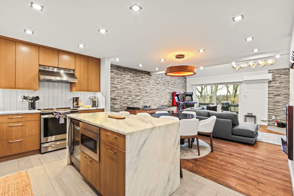 Open-concept living, dining, and kitchen area! Features a waterfall island, coffee maker, mini fridge, and AC. Enjoy seamless access to our indoor game space with arcade machines and shuffleboard. Your ideal dog-friendly Pocono getaway.