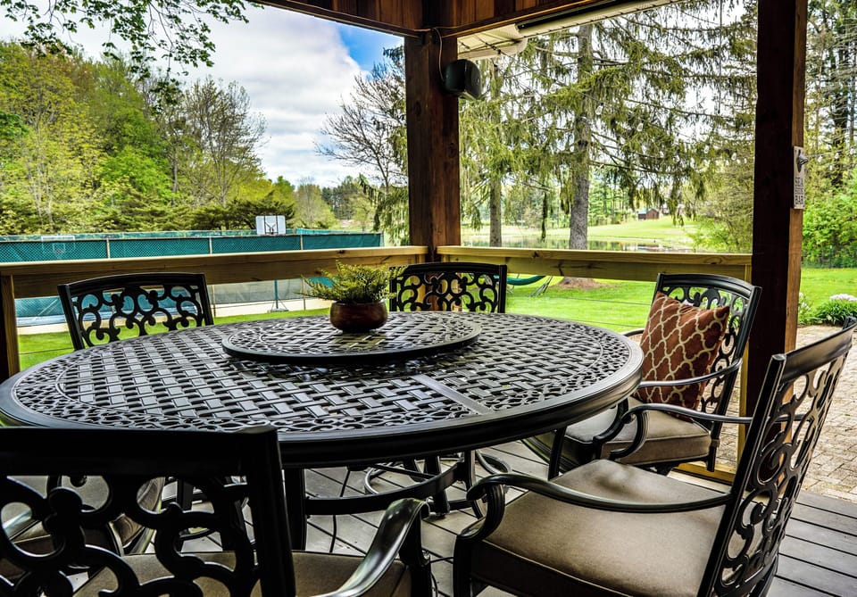 The Retreat: Back porch dining off the Patio with seating. Leading to the Sauna and Hot tub, further back in the yard. 