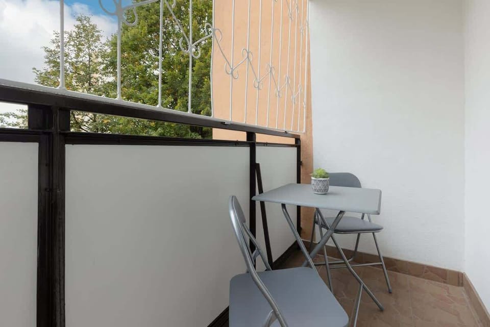 A cozy balcony with a small table and chairs, offering a private outdoor retreat surrounded by greenery.
