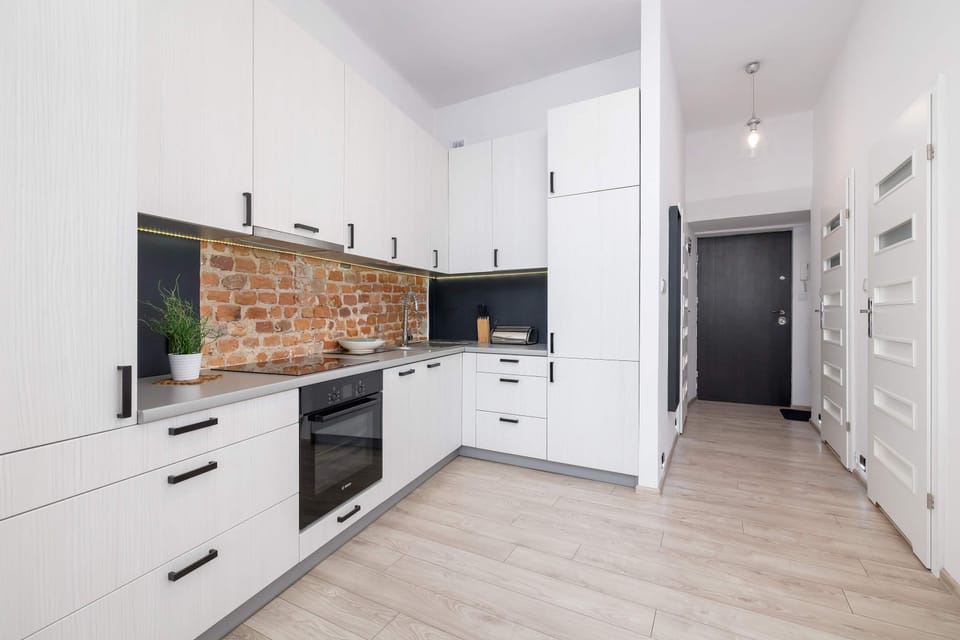 A modern kitchen featuring white cabinets, a brick backsplash, and built-in appliances for a stylish and functional design.
