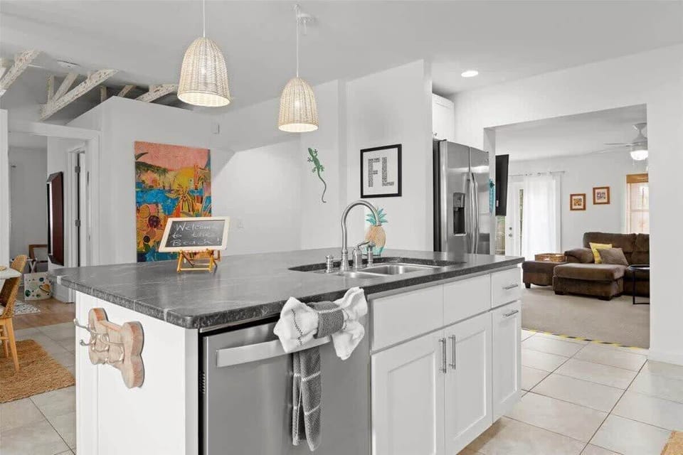 Modern kitchen island with dark countertop and pendant lighting overlooking the living area.