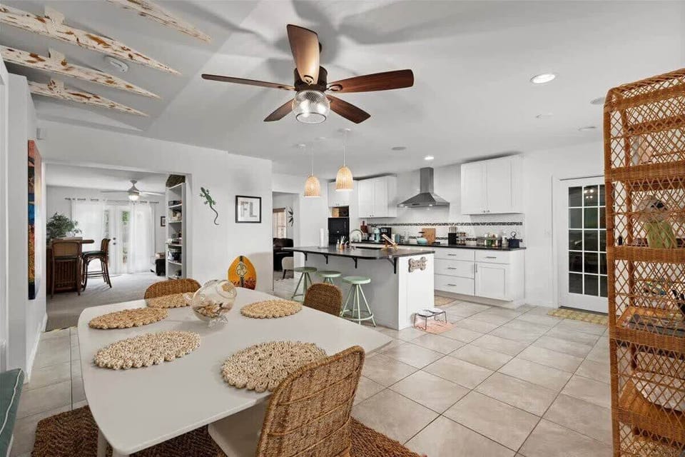 Open kitchen and dining area with modern white cabinetry and a ceiling fan