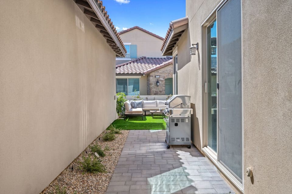 Side patio w/ grill & narrow seating area, ideal for casual outdoor cooking
