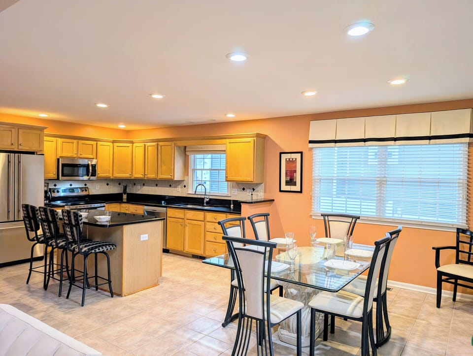 109 Soft Shell Cove - Kitchen and Dining Space with Breakfast Ba - A perspective of the open-concept kitchen highlighting the wooden cabinetry, dark countertops with bar seating, and an adjacent dining area.