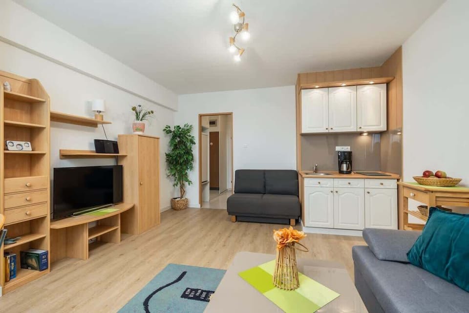 A wide view of the living room, emphasizing its spacious layout and wooden furnishings.

