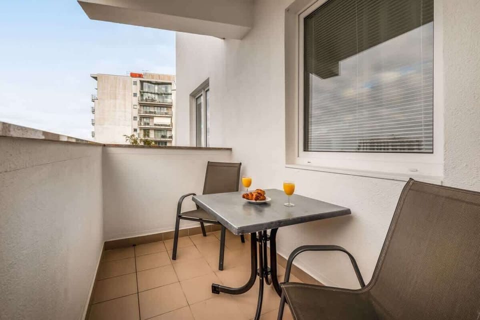 A cozy balcony setup with chairs, a table, and a view, perfect for enjoying coffee outdoors.

