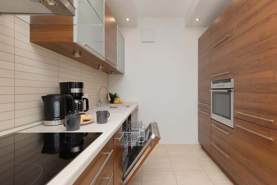 A modern kitchen featuring dark wooden cabinets, light countertops, and sleek appliances, blending functionality with a contemporary design.