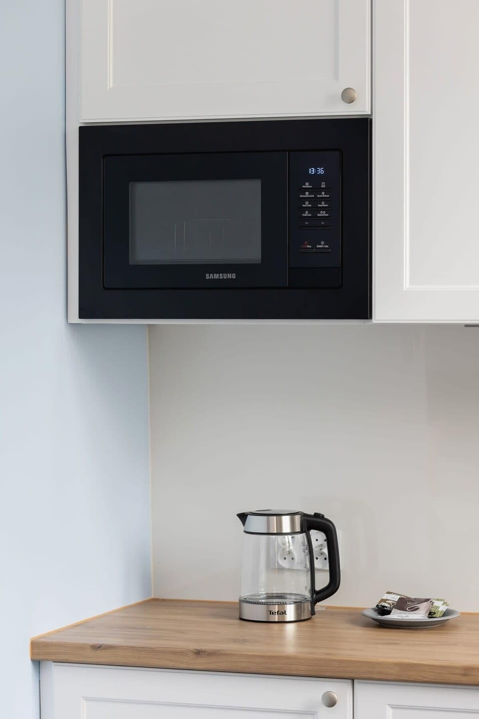 A kitchen corner with a microwave, sink, and compact appliances integrated into the space.
