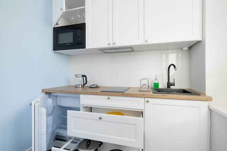 A kitchen corner with a microwave, sink, and compact appliances integrated into the space.
