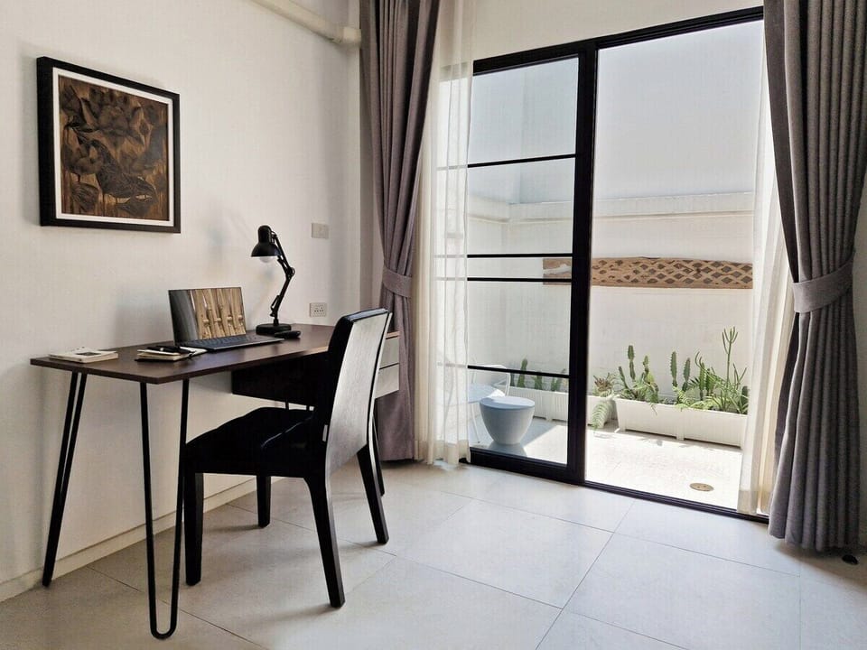Stylish workspace with a modern desk and chair, complemented by natural light streaming in through sliding doors. Step outside to a serene patio with greenery, offering a peaceful break from work or planning your next adventure.