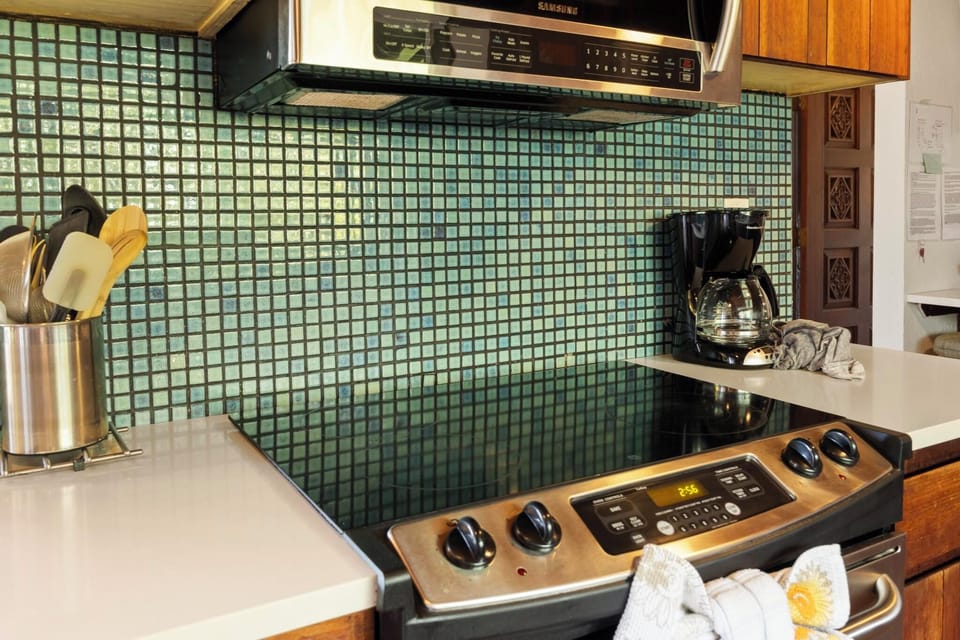 Enjoy cooking in style with a mosaic backsplash adding a pop of color to this well-equipped kitchen with modern amenities.