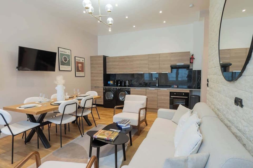Salon avec canapé lit (deux personnes), smart tv, coin repas et cuisine ouverte équipée
