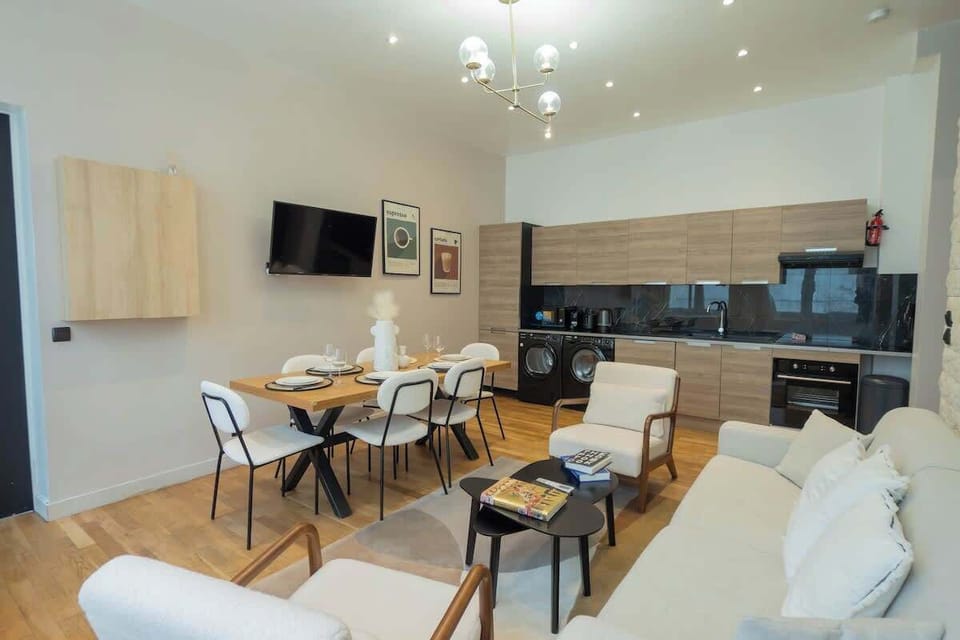 Salon avec canapé lit (deux personnes), smart tv, coin repas et cuisine ouverte équipée
