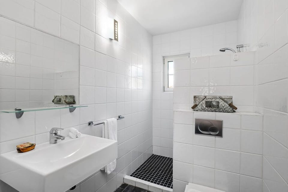 An all white bathroom with a touch of black floors are simply classic. Clean and airy, light and bright!