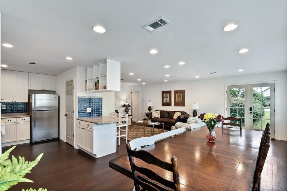 Open Kitchen, Dining, and Living Layout - Wide view showing the connected kitchen, dining table, breakfast bar, and living room.