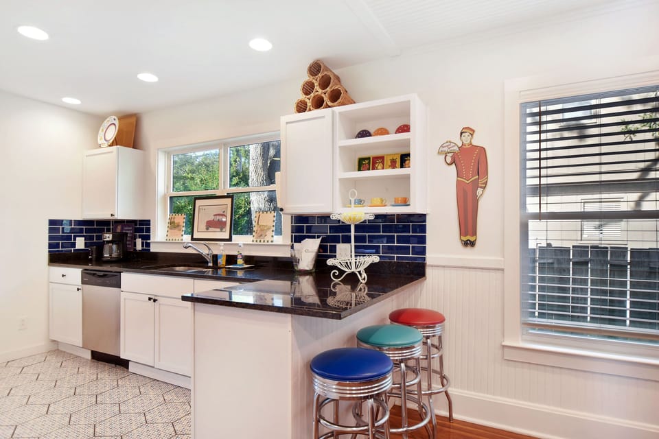 Breakfast Bar And Navy Tile Kitchen - Colorful stools, granite counters, and stainless appliances give the kitchen a practical spot for coffee, snacks, and quick meals.