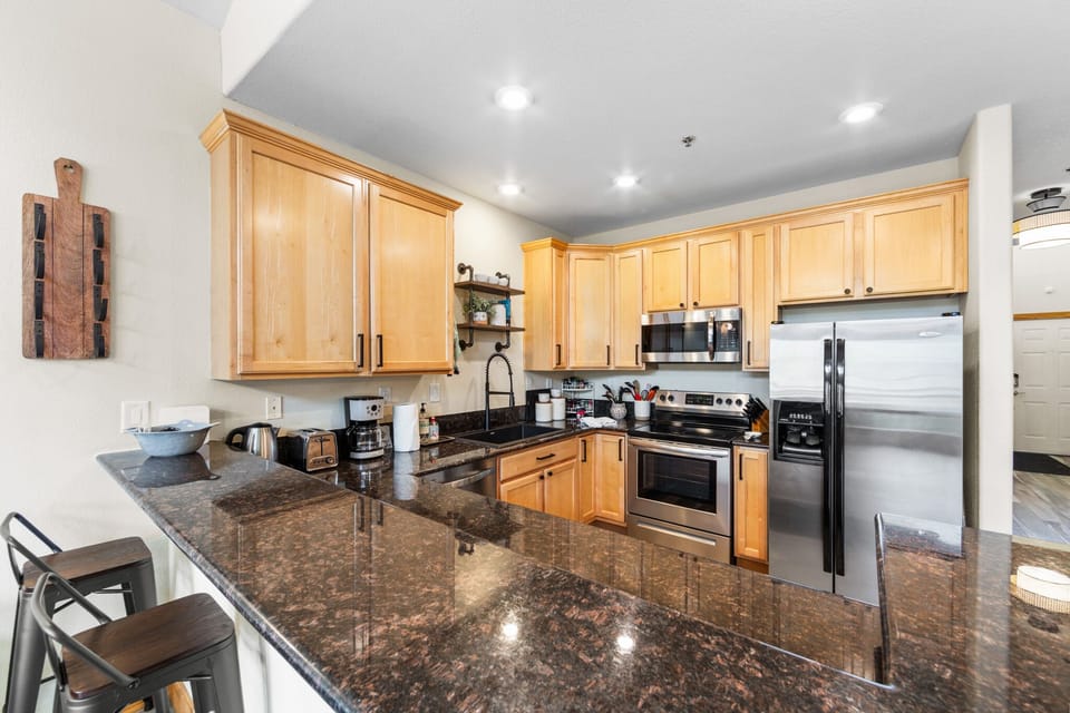 Your gourmet kitchen awaits with granite countertops, stainless steel appliances, and warm wood cabinetry perfect for cooking memorable meals together.