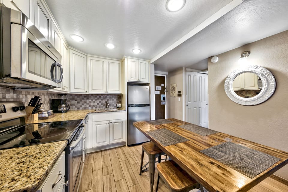 Your fully equipped kitchen awaits with granite counters, stainless appliances, and a rustic dining table perfect for memorable meals.