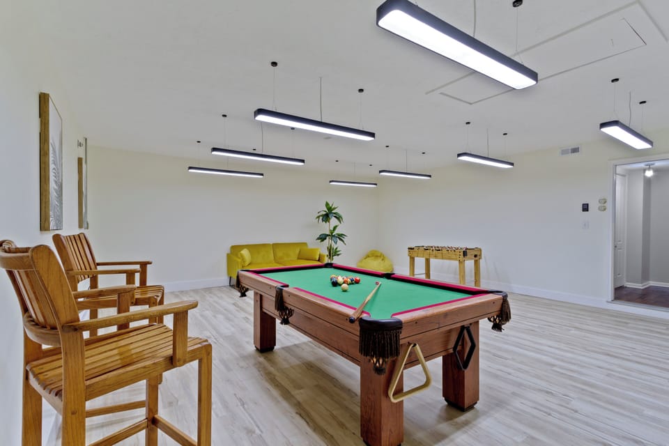 Pool table-centered space with cozy seating and bright lighting.