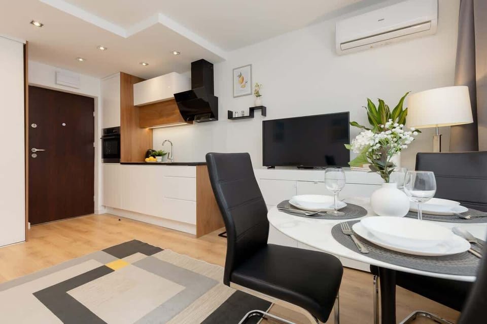 A dining area with a table set for two, featuring fresh flowers and modern place settings.
