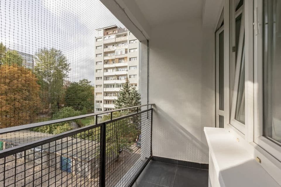 A balcony view with a railing, overlooking the surrounding buildings and greenery for relaxation.
