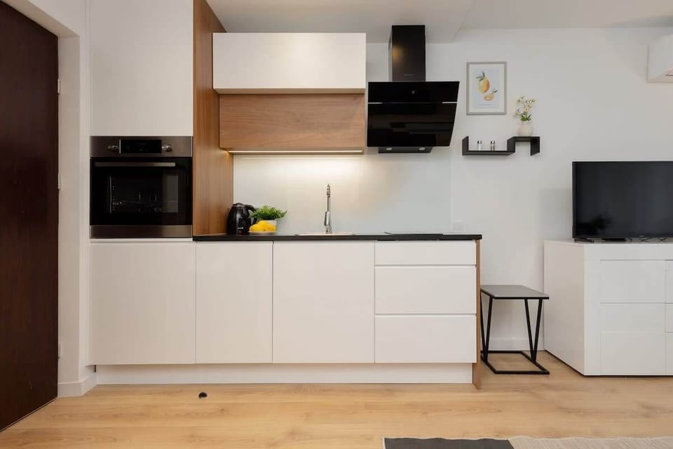 A compact kitchen with built-in appliances, white cabinets, and wooden accents for a clean design.
