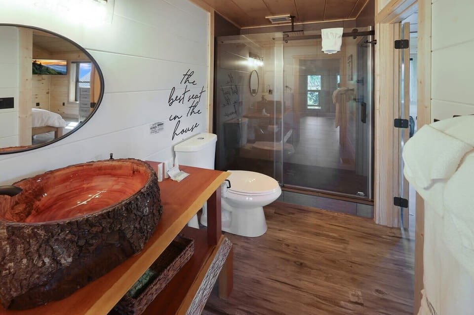 Rustic bathroom featuring a unique wood sink and a glass-enclosed shower.