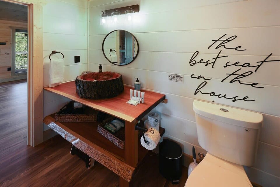 Rustic bathroom featuring a unique wood sink and modern lighting.