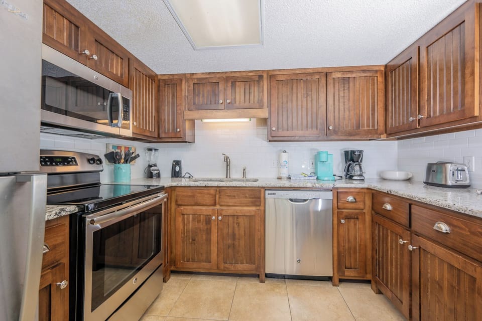Kitchen features rich wooden cabinetry, granite countertops, stainless appliances, Keurig and coffee maker