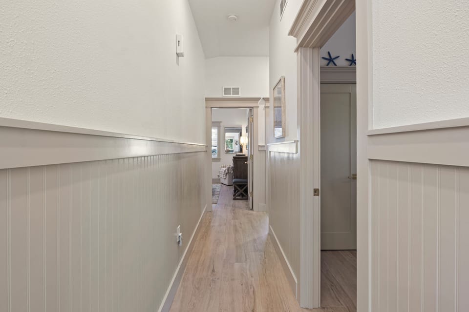 Walk down your private hallway with coastal charm, where beautiful wainscoting and warm wood floors lead to your comfortable living spaces.