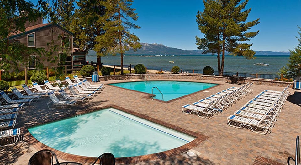 Lakefront resort pool area with stunning lake and mountain views, perfect for relaxing waterside vacations.
