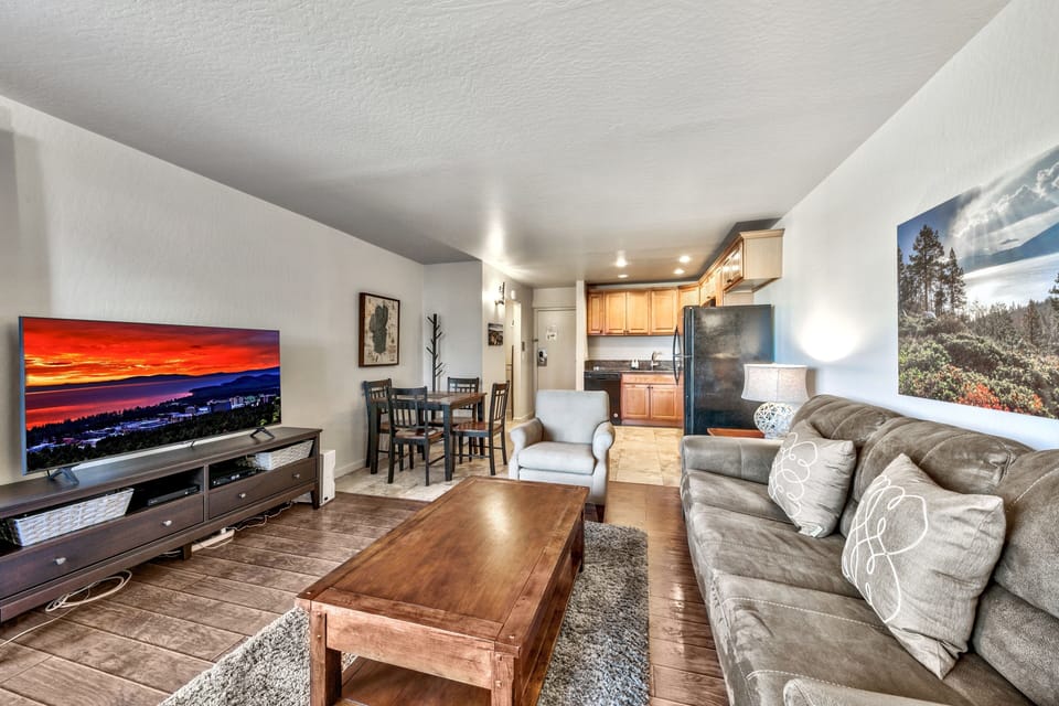 Unwind in your spacious living room with plush seating, large TV, and open kitchen—perfect for relaxing evenings.