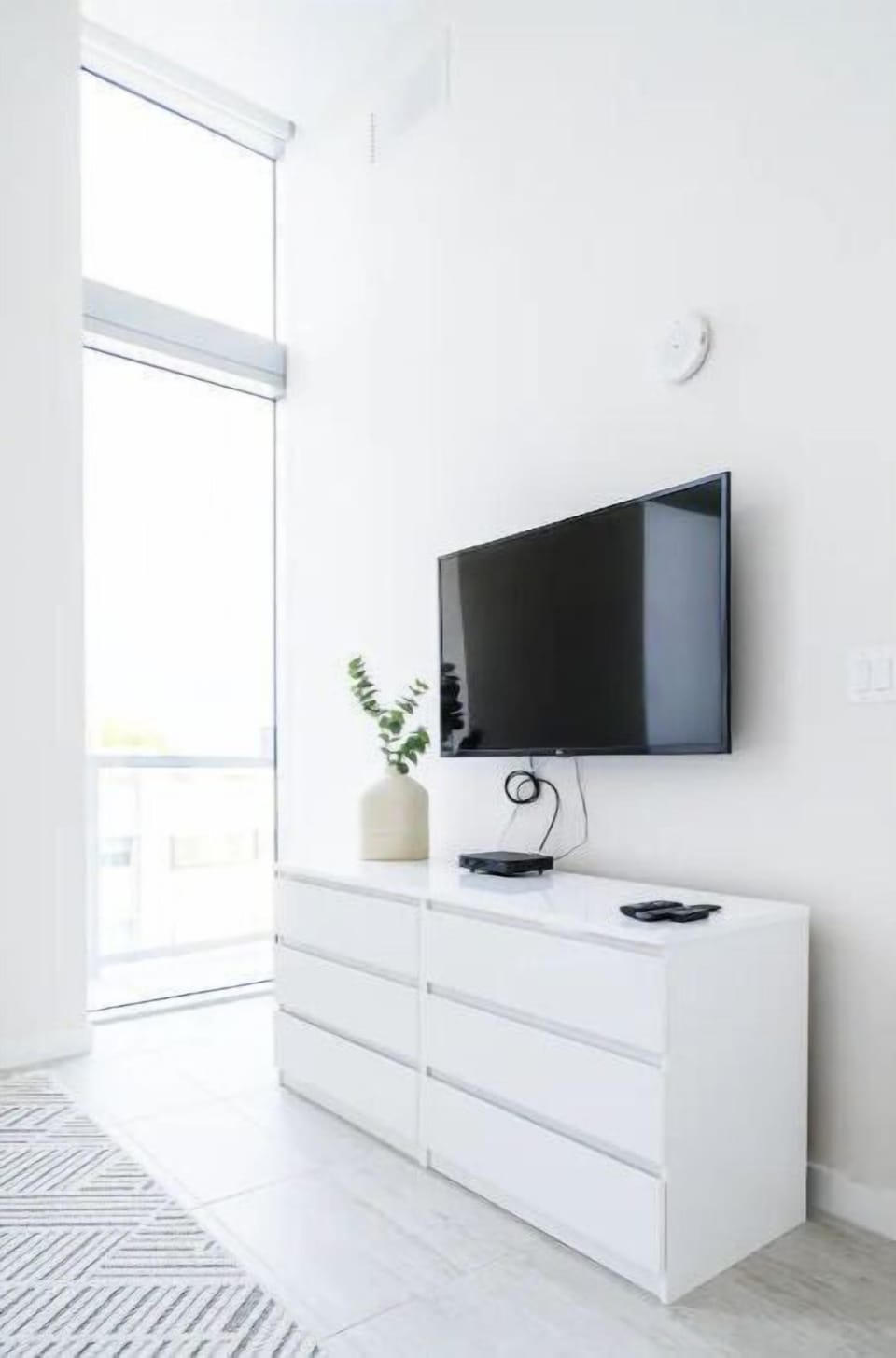 Wall-mounted TV above a sleek dresser.