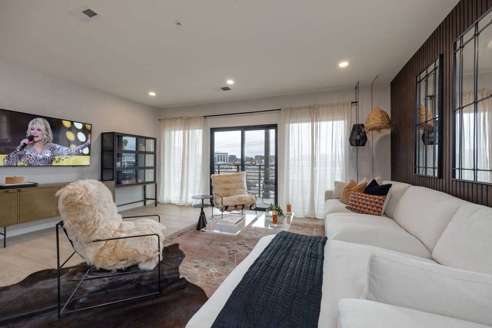 Cozy modern living room featuring a Smart TV, Patio access with city views and designer decor with plush furnishings.