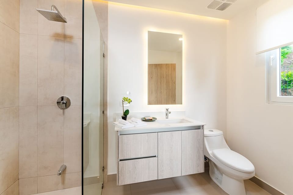 Modern ensuite bathroom in a Tamarindo, Costa Rica vacation rental featuring a spacious walk-in glass shower and contemporary finishes. A clean, comfortable private bathroom designed for families and guests enjoying a relaxing beach vacation.