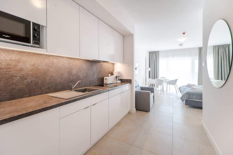 A modern kitchen with white cabinets, stone countertops, and built-in appliances, designed for both style and efficiency.


