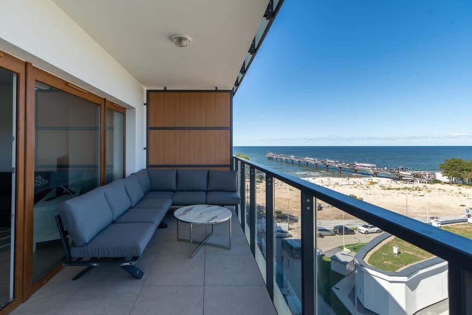A spacious balcony with a comfortable seating area, overlooking a scenic view of the beach and coastline.
