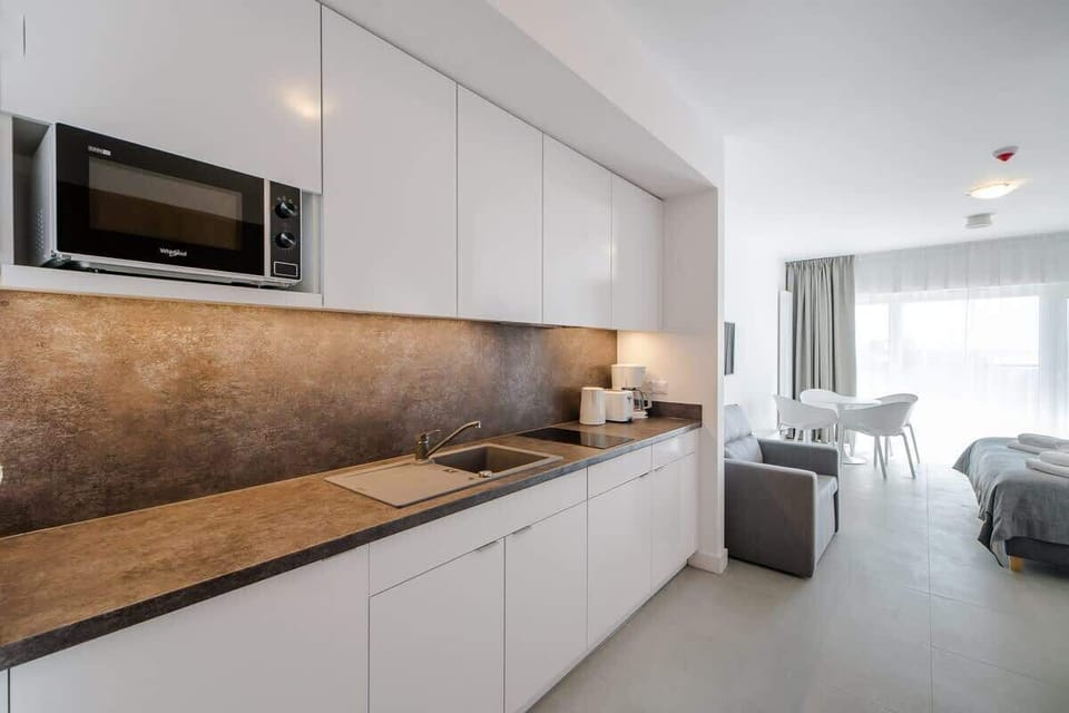 A modern kitchen with sleek white cabinets, a wooden countertop, and built-in appliances, designed for functionality and style.
