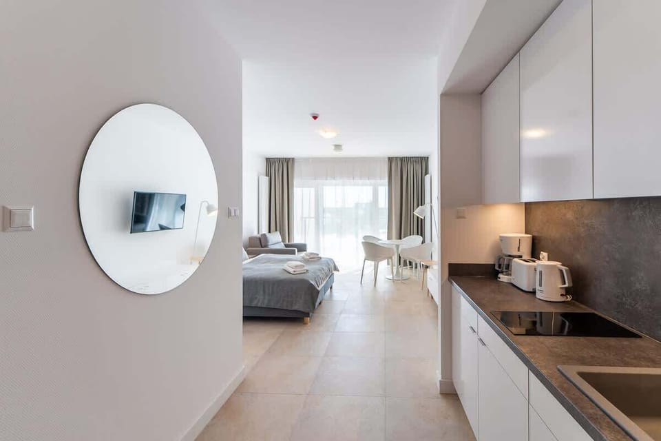 A round mirror in a hallway leading to the living and kitchen area, enhancing the spacious and bright atmosphere.

