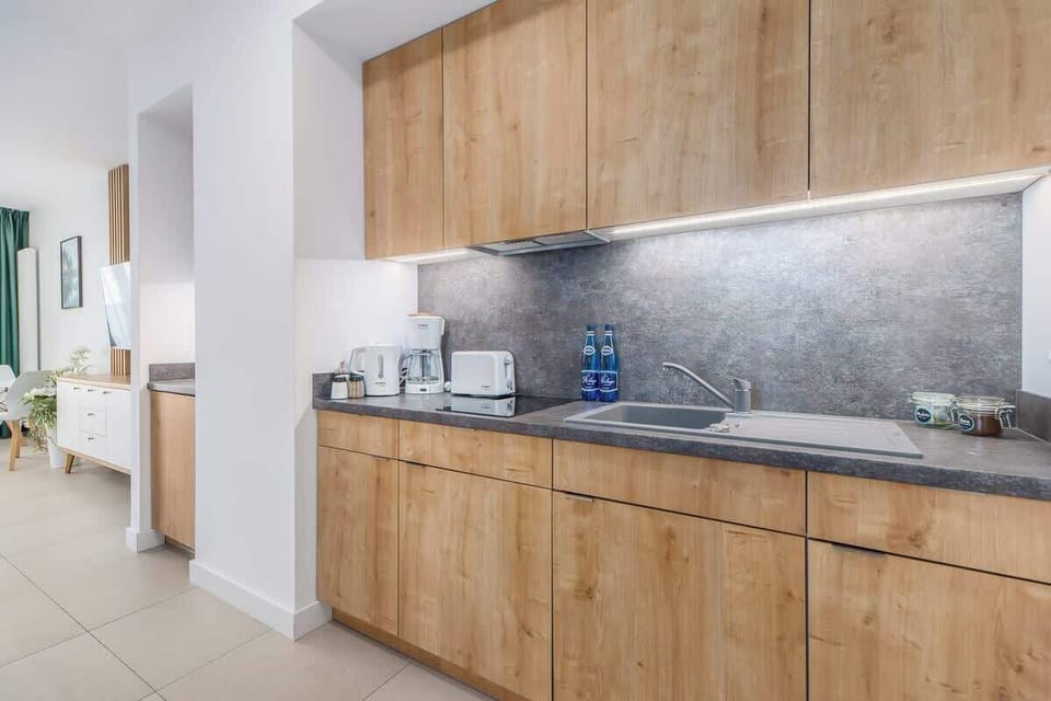 A stylish kitchen with wooden upper cabinets, a sleek gray countertop, and modern appliances, blending elegance with functionality.
