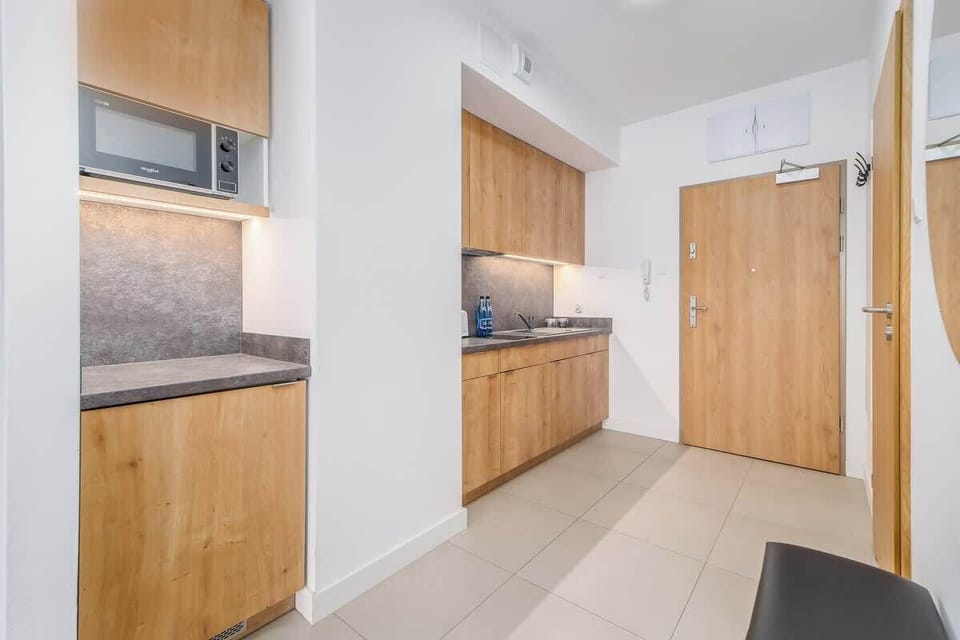 A compact kitchen with wooden cabinets, a gray backsplash, and sleek appliances, offering a practical and stylish design.
