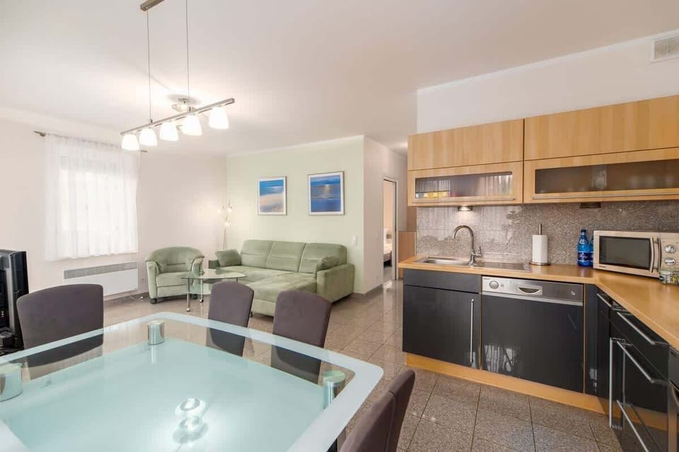 A dining area with a glass table, modern chairs, and an open connection to the kitchen.
