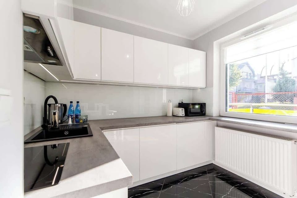 A sleek kitchen with white cabinetry, modern appliances, and a clean design, perfect for cooking and hosting.
