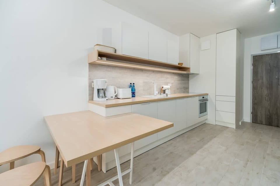 A dining area adjacent to the kitchen, featuring a light wooden table and matching chairs.
