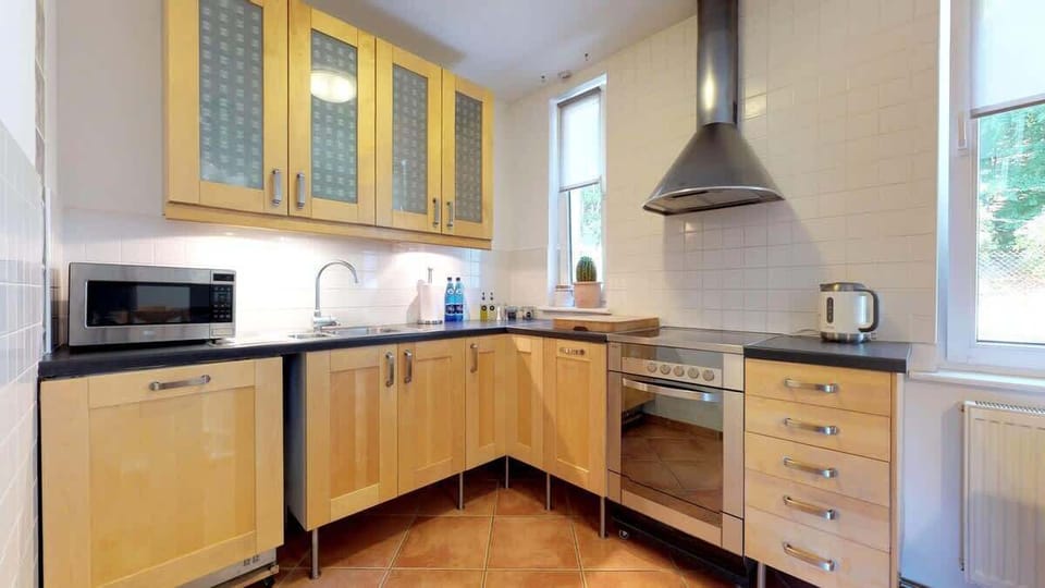 A modern kitchen with wooden cabinets, built-in appliances, and a dining area for four.
