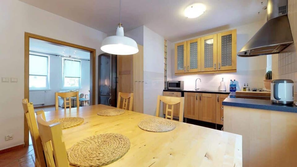 A dining area next to the kitchen, featuring a wooden table, wicker placemats, and pendant lighting.






