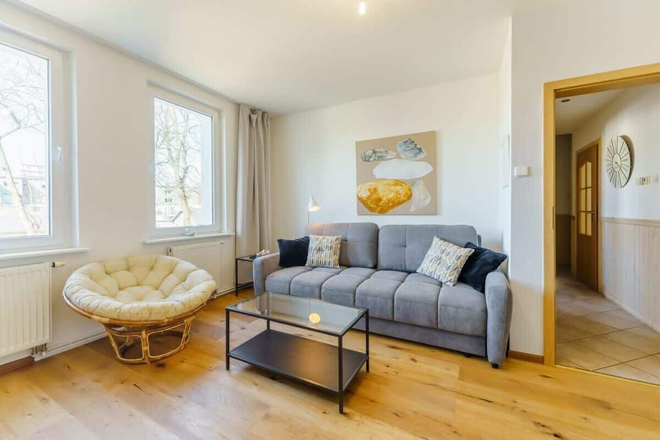 A wide-angle view of the living room with a gray sofa, decorative art, and a comfortable armchair.
