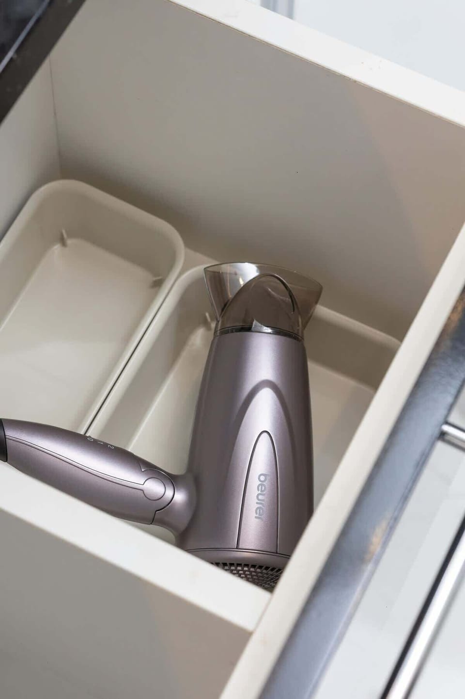 An open drawer holding a hairdryer and additional bathroom amenities, neatly organized.
